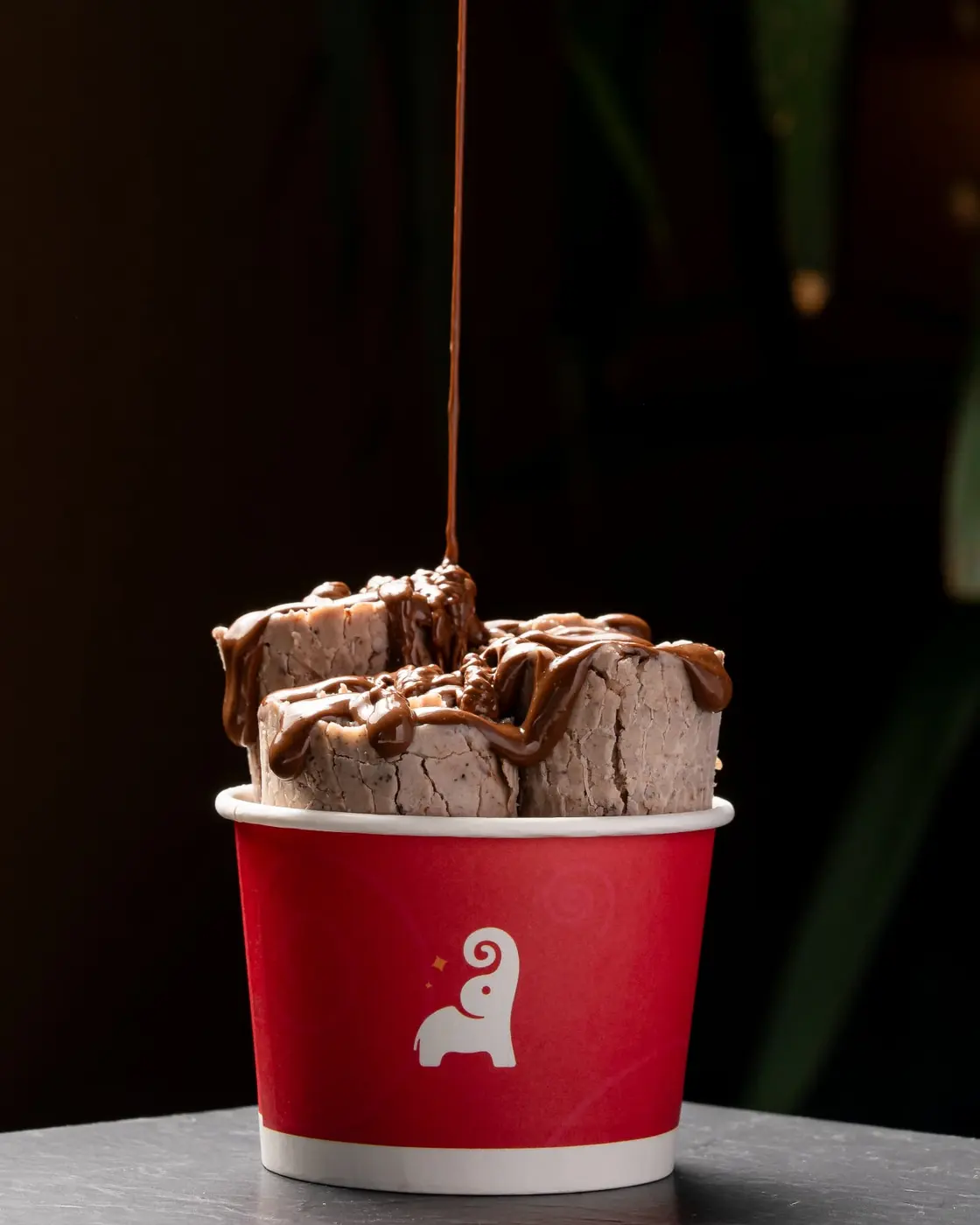 Chocolate sauce poured over Tai Sweets rolled ice cream in a branded cup